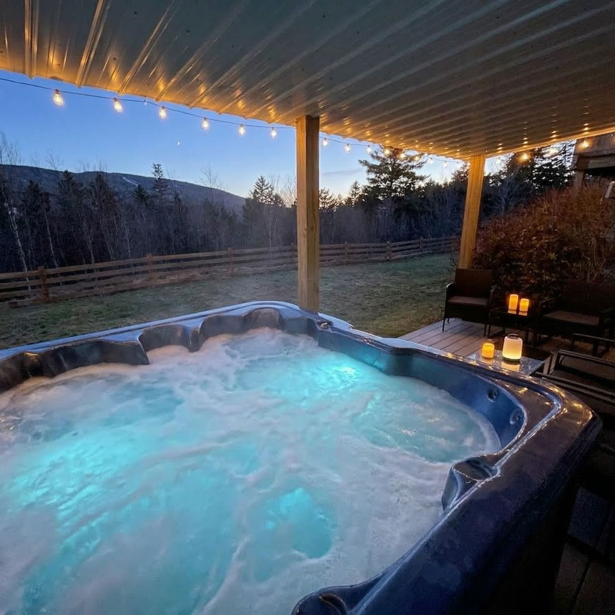 Private outdoor hot tub on a Bretton Woods vacation rental deck at dusk with snowcapped White Mountains in the background
